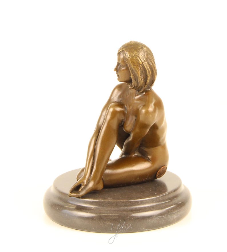 May include: Bronze sculpture of a seated figure with short hair, resting on a dark, round base. The figure is posed with one leg bent and the other extended, with a smooth, polished finish. The sculpture is a classic art piece.