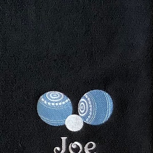 K&ouml;nnte beinhalten: Schwarzes Handtuch mit zwei blauen und wei&szlig;en Bowlingkugeln und dem Namen "Joe" in wei&szlig; gestickt.