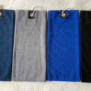 K&ouml;nnte beinhalten: Vier Mikrofaser-Golft&uuml;cher in verschiedenen Farben: marineblau, grau, royalblau und schwarz. Jedes Handtuch hat einen Metallhaken und eine schwarze Schlaufe.
