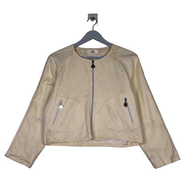 K&ouml;nnte beinhalten: Eine gelbe Jacke mit wei&szlig;em Muster und Rei&szlig;verschluss. Die Jacke hat zwei Taschen mit Rei&szlig;verschl&uuml;ssen auf der Vorderseite.
