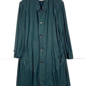 Może przedstawiać: Długi, ciemnozielony płaszcz z zapięciem na guziki, kołnierzem i kieszeniami. Płaszcz wykonany jest z jednolitego materiału. Płaszcz wisi na białym wieszaku.