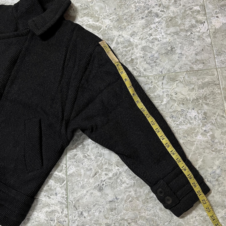 Puede incluir: Chaqueta negra con tejido texturizado, con cuello ancho y un solo bolsillo. La longitud de la manga es de aproximadamente 51 cm, medida con una cinta m&eacute;trica. La chaqueta tiene dos botones en el pu&ntilde;o.