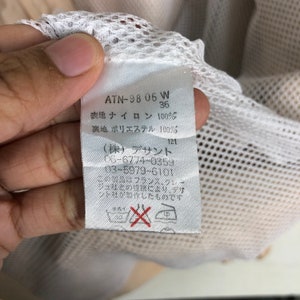 May include: White tag with black text that reads "ATN-98 05 W 36", "表地 ナイロン 100%", "裏地 ポリエステル 100%", "(株) デサント 06-6774-0359 03-5979-6101", "この製品はフランス、クレー ジュ社との提壊により、デザ ント社が製作したものです".
