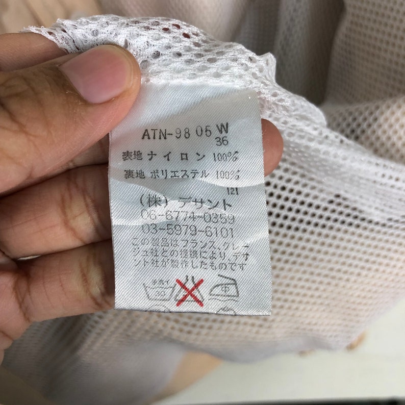 May include: White tag with black text that reads "ATN-98 05 W 36", "表地 ナイロン 100%", "裏地 ポリエステル 100%", "(株) デサント 06-6774-0359 03-5979-6101", "この製品はフランス、クレー ジュ社との提壊により、デザ ント社が製作したものです".