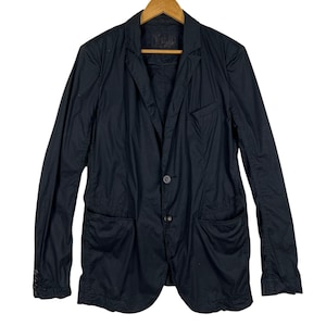 May include: Black blazer with two front pockets, a notched lapel, and a two-button closure. The jacket is made of a lightweight fabric and has long sleeves. The blazer is hanging on a wooden hanger.