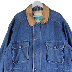 May include: A blue denim jacket with a brown leather collar and two large flap pockets. The jacket has a button closure and a label that reads "Great River".