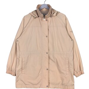 May include: A beige hooded jacket with a zipper and button closure. The jacket has two pockets and a drawstring waist.