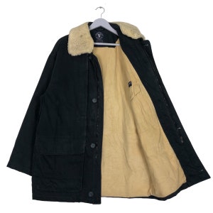 Pode incluir: Uma jaqueta preta com gola de pele sintética marrom. A jaqueta tem fecho de zíper e vários bolsos. O forro é de cor marrom claro.