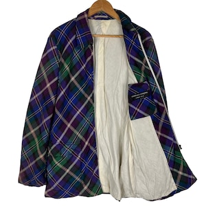 Puede incluir: Una chaqueta de cuadros azules, verdes y morados con cierre de cremallera. La chaqueta tiene un forro blanco y un peque&ntilde;o bolsillo en el interior. La etiqueta dice "COMME des GARCONS HOMME PLUS".