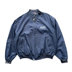 Puede incluir: Chaqueta bomber azul marino con cuello alzado y cremallera completa. La chaqueta tiene dos bolsillos delanteros y puños y dobladillo elásticos. El texto "GOLD MEDAL" está bordado en el pecho. Una prenda de abrigo informal clásica.