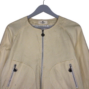 K&ouml;nnte beinhalten: Eine gelbe Jacke mit wei&szlig;em Muster, Rei&szlig;verschluss und Logo auf der Vorderseite. Die Jacke hat zwei Taschen mit Rei&szlig;verschl&uuml;ssen auf der Vorderseite.