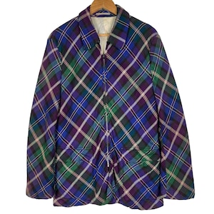 Puede incluir: Una chaqueta de cuadros azules, verdes y morados con cierre de cremallera y dos bolsillos delanteros.