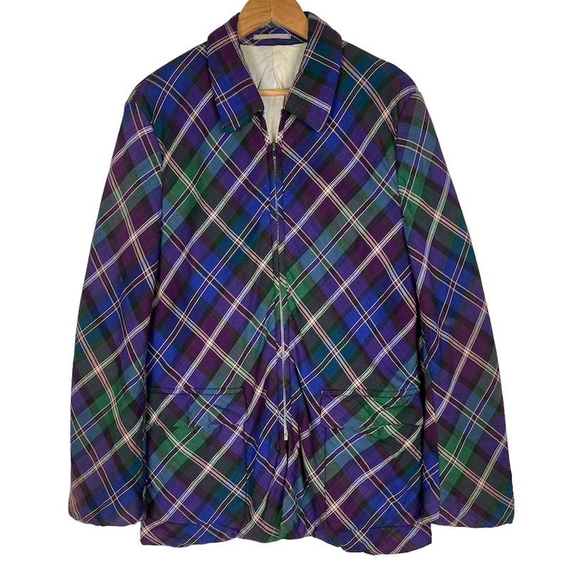 Puede incluir: Una chaqueta de cuadros azules, verdes y morados con cierre de cremallera y dos bolsillos delanteros.