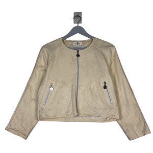 K&ouml;nnte beinhalten: Eine gelbe Jacke mit wei&szlig;em Muster, Rei&szlig;verschluss und zwei Taschen. Die Jacke hat einen runden Ausschnitt und lange &Auml;rmel.
