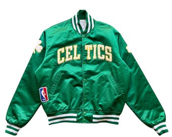 May include: Green satin jacket with the word "CELTICS" in gold lettering. The jacket features white and green striped cuffs and collar, along with a team logo patch and shamrock details. A vintage-style sports jacket.