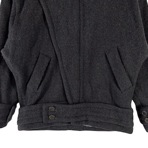 Puede incluir: Chaqueta de lana gris oscuro con tejido texturizado. La chaqueta presenta dos bolsillos delanteros, pu&ntilde;os abotonados y una cinturilla abotonada. El dise&ntilde;o de la chaqueta es cl&aacute;sico y a medida, adecuada para climas m&aacute;s fr&iacute;os.