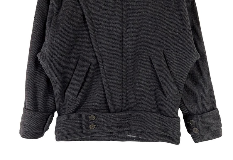 Puede incluir: Chaqueta de lana gris oscuro con tejido texturizado. La chaqueta presenta dos bolsillos delanteros, pu&ntilde;os abotonados y una cinturilla abotonada. El dise&ntilde;o de la chaqueta es cl&aacute;sico y a medida, adecuada para climas m&aacute;s fr&iacute;os.