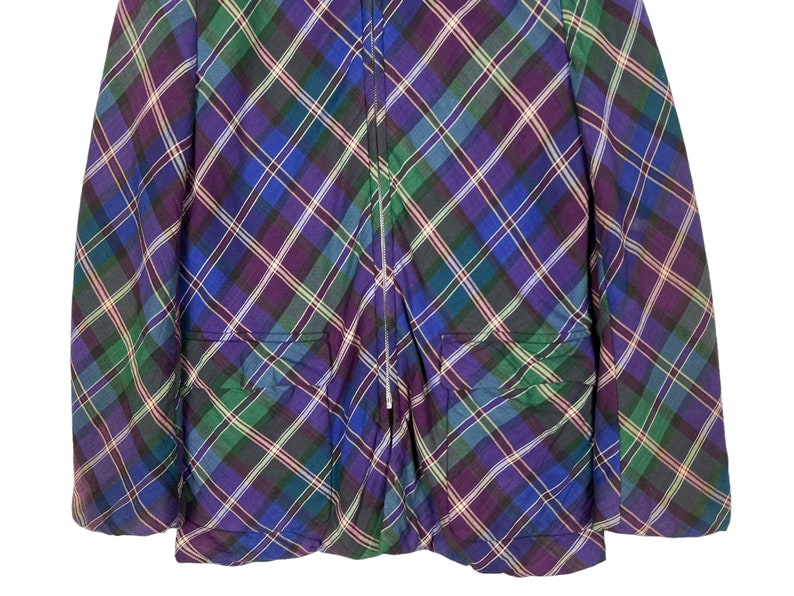 Puede incluir: Una chaqueta de cuadros de color morado, verde y azul con cierre de cremallera y dos bolsillos.