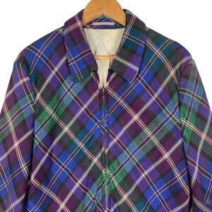 Puede incluir: Una chaqueta de cuadros de color morado, azul y verde con cierre de cremallera.