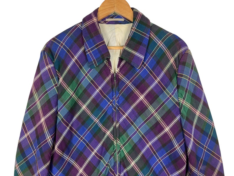 Puede incluir: Una chaqueta de cuadros de color morado, azul y verde con cierre de cremallera.