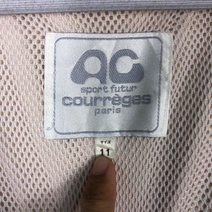 May include: White label with black text that reads "sport futur courr&egrave;ges paris" and a logo of the letters "ac" in a circle. The label is attached to a white mesh fabric with a white tag that reads "11" in black.