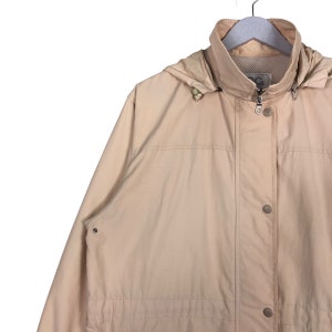 May include: A beige hooded jacket with a zipper closure and multiple pockets. The jacket has a drawstring hood and a relaxed fit.
