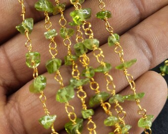 May include: Close-up of several strands of peridot gemstone beads. The beads are a vibrant green colour and are strung on delicate gold-coloured chains. The peridot stones are irregularly shaped and have a natural, raw appearance.