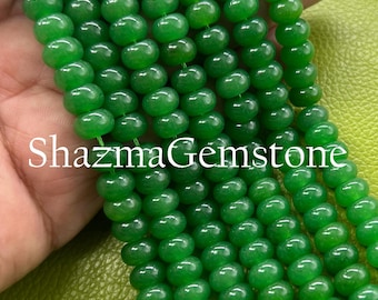 May include: Close-up of several strands of bright green gemstone beads. The beads are spherical and polished, with a shiny surface. The text "ShazmaGemstone" is visible. The beads are strung together, possibly for jewellery making or crafts.