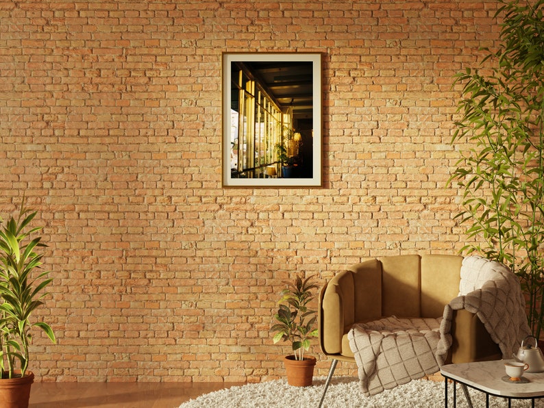 Puede incluir: Un sill&oacute;n marr&oacute;n con una manta de tiro blanca y marr&oacute;n se encuentra frente a una pared de ladrillo. Un cuadro enmarcado de una ventana con luz que entra por ella cuelga de la pared. Una peque&ntilde;a planta en maceta se encuentra en el suelo frente al sill&oacute;n.