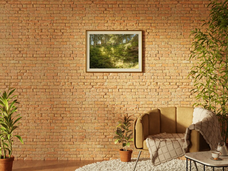 May include: A brown armchair with a white throw blanket sits in front of a brick wall. A framed picture of a forest scene hangs on the wall. A potted plant sits on the floor next to the chair.