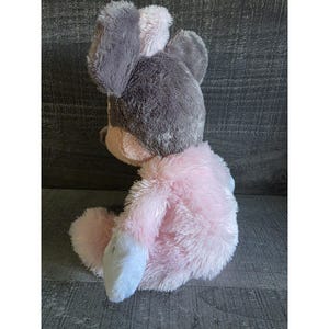 May include: A plush toy in the shape of a mouse, featuring a gray head with pink ears and a pink body. The toy has a soft, fluffy texture and is designed to sit upright.