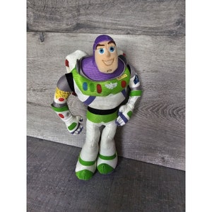 Peut inclure: Un jouet en peluche de Buzz l'&Eacute;clair de la franchise Toy Story. Le jouet porte sa combinaison de ranger spatial signature avec un casque violet, des accents verts et blancs, et un patch jaune qui indique "SPACE RANGER".