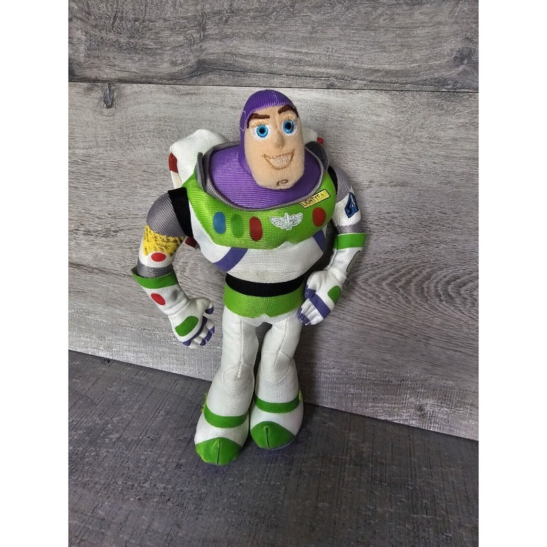 Peut inclure: Un jouet en peluche de Buzz l'&Eacute;clair de la franchise Toy Story. Le jouet porte sa combinaison de ranger spatial signature avec un casque violet, des accents verts et blancs, et un patch jaune qui indique "SPACE RANGER".