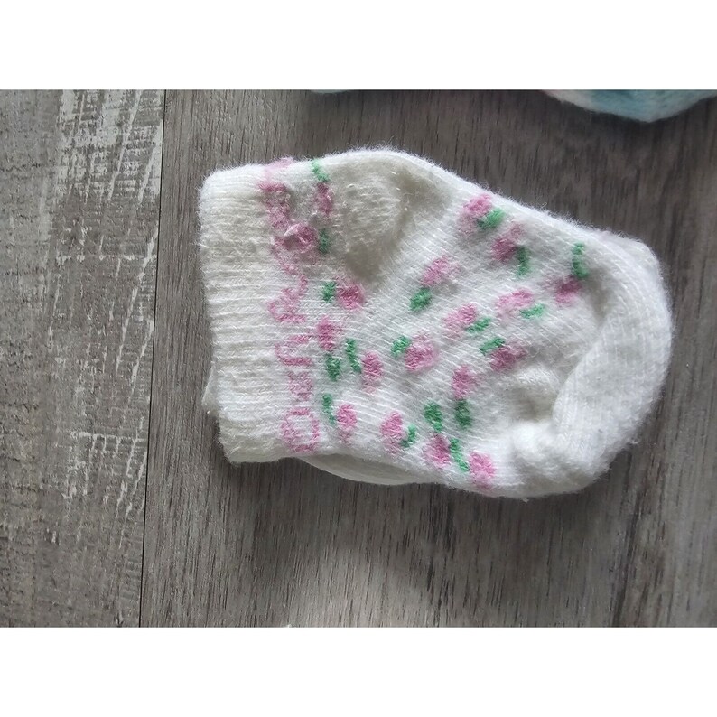 Puede incluir: Un calcet&iacute;n blanco con un estampado floral rosa y verde.