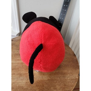May include: Red and black plush toy shaped like Mickey Mouse. The toy has a long black tail and large black ears.