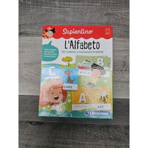May include: A colorful box for a children's alphabet puzzle game. The box features a cartoon illustration of a child and the text "Sapientino L'Alfabeto Per imparare a riconoscere le lettere 3-5 anni Clementoni".