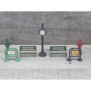 May include: Miniature street scene set with a clock tower, benches, a fire hydrant, and signs that read "Clearance Sale" and "Road Closed." The clock tower is black with a white clock face. The benches are green.