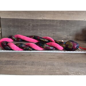 Op de afbeelding: Een witte keramische mok met een zwarte handgreep en de tekst "But First, Coffee" in een vetgedrukte, zwarte letter. De mok staat tegen een wazige achtergrond, wat een gezellige omgeving suggereert.