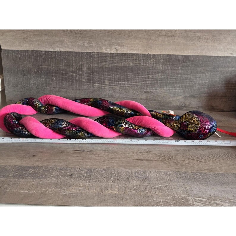 Op de afbeelding: Een witte keramische mok met een zwarte handgreep en de tekst "But First, Coffee" in een vetgedrukte, zwarte letter. De mok staat tegen een wazige achtergrond, wat een gezellige omgeving suggereert.