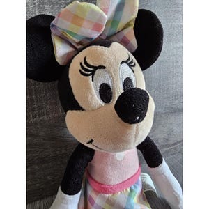 K&ouml;nnte beinhalten: Ein Pl&uuml;schtier von Minnie Mouse, das ein rosa-wei&szlig; kariertes Kleid mit einer passenden Schleife im Haar tr&auml;gt. Ihre Augen sind gestickt und sie hat eine schwarze Nase.