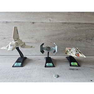 May include: Three Star Wars spacecraft models on display stands. The models are a white TIE Interceptor, a black TIE Advanced x1, and a white Snowspeeder. Each stand has the Star Wars logo and the words "Collector's Edition".
