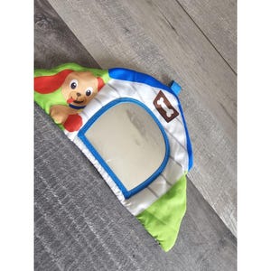 May include: A colorful baby toy shaped like a dog house. The toy features a smiling cartoon puppy, a mirror, and a bone-shaped emblem. The dog house is white with blue and green accents.