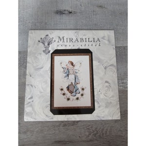 May include: Cross stitch pattern featuring a fairy with blue wings and a white dress, surrounded by flowers. The pattern is titled "Mirabilia cross-stitch".