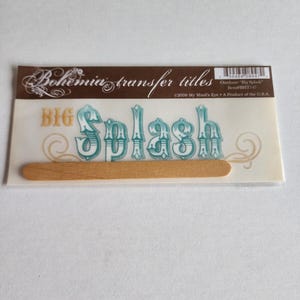 May include: A package of Bohemia transfer titles featuring the text BIG Splash in teal and gold lettering. The set includes a wooden applicator stick and is labeled with the product name, item number BHT147, and a copyright date of 2006.