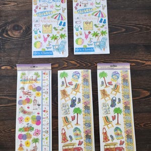 Puede incluir: Cinco hojas verticales de pegatinas decorativas con ilustraciones de temática playera. Los diseños incluyen palmeras, sillas de playa, tablas de surf, chanclas y vehículos. El texto incluye "Fun in the Sun", "Surf's On" y "life's a beach!" en varias fuentes coloridas.