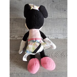 K&ouml;nnte beinhalten: Ein Pl&uuml;schtier von Minnie Mouse, die ein rosa Kleid mit einem karierten Rock und einer rosa Schleife auf dem Kopf tr&auml;gt.