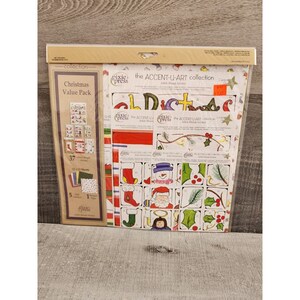 May include: A Christmas value pack of paper crafting supplies from Pixie Press. The pack includes 37 sheets of 12x12 inch paper, 5 sheets of 12x12 inch cardstock, and 1 sheet of 12x12 inch glitter paper. The pack also includes a set of die-cut embellishments with a Christmas theme.