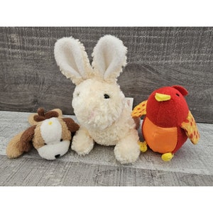 May include: Three plush toys: a white bunny, a brown and white dog, and a red bird with orange and yellow accents. The toys are soft and cuddly, perfect for children.