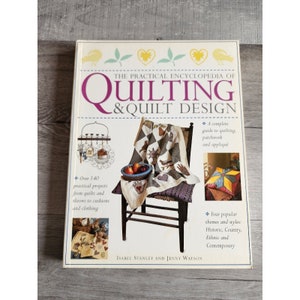 Könnte beinhalten: Ein Buch mit dem Titel "The Practical Encyclopedia of Quilting & Quilt Design" von Isabel Stanley und Jenny Watson. Der Umschlag zeigt eine Steppdecke auf einem Stuhl, eine Schale mit Obst und verschiedene Steppprojekte. Das Buch enthält über 140 praktische Projekte, von Steppdecken und Überwürfen bis hin zu Kissen und Kleidung. Es enthält auch eine vollständige Anleitung zum Quilten, Patchwork und Applizieren sowie vier beliebte Themen und Stile: Historisch, Ländlich, Ethnisch und Zeitgenössisch.