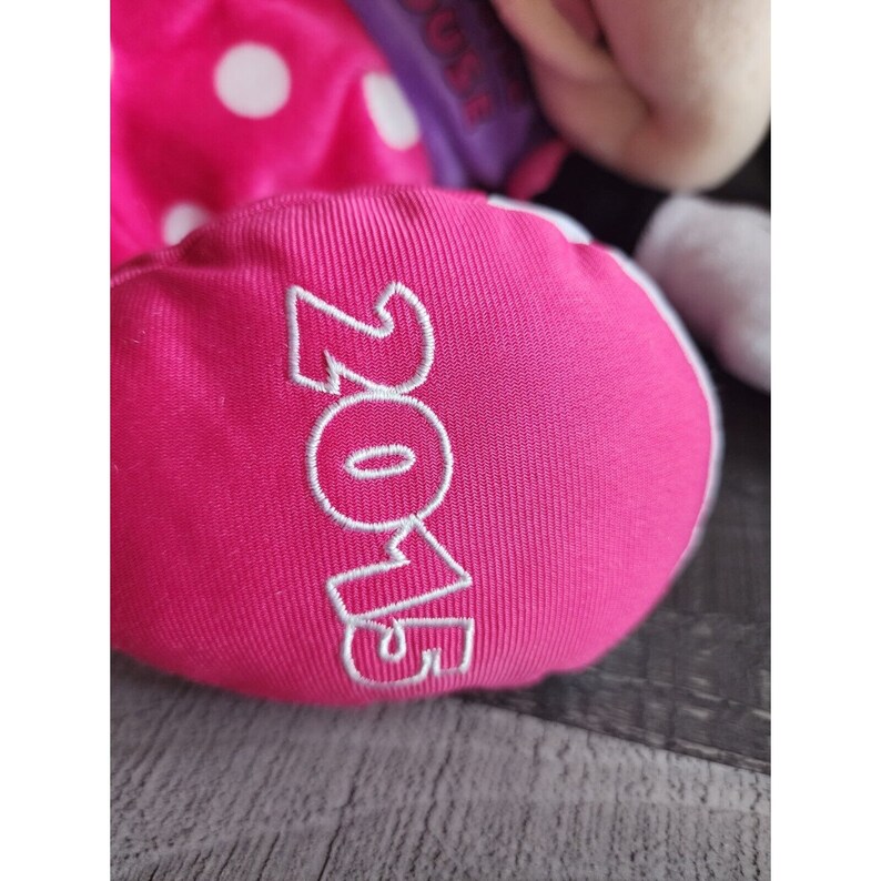 May include: Pink fabric with white polka dots and the word "ZOE" embroidered in white.